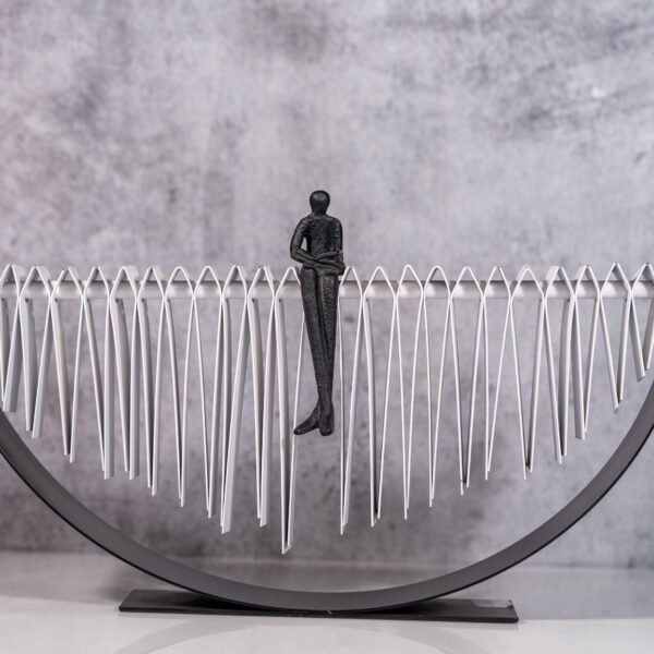 A Solitary Figure Navigating the Undulating Path of Life's Complexities, Symbolized by a Modern Metal Sculpture of Balance and Introspection