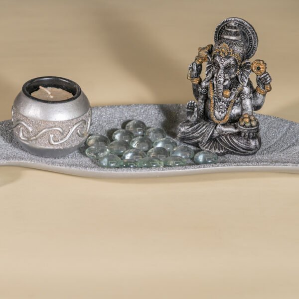 A Serene Ganesha Idol and Candle Holder Arrangement on a Decorative Silver Tray with Clear Glass Pebbles, Evoking a Sense of Peace and Spiritual Ambiance.