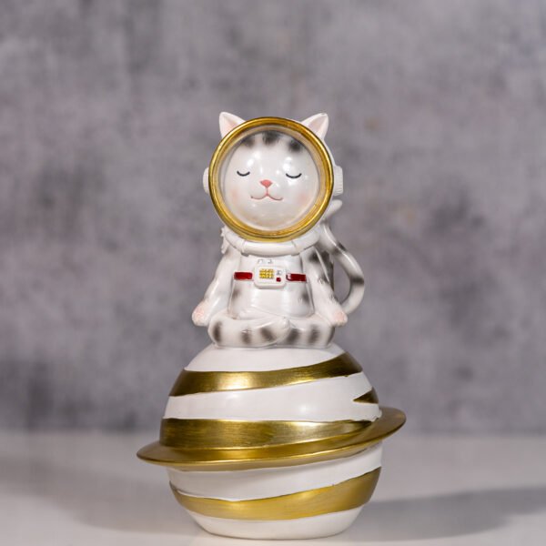 A whimsical Ceramic Astronaut cat Figurine Perched Atop a Golden-Ringed Celestial Body