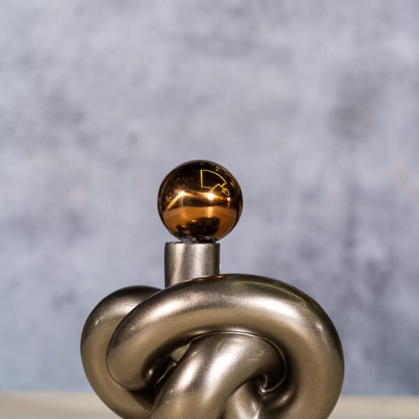 A Glimmering Spherical Topped Metal Knot Sculpture