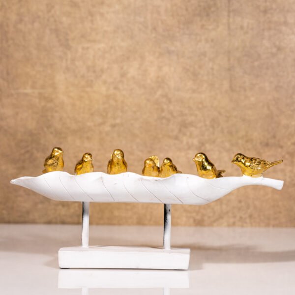 A Decorative White Leaf-shaped tray Adorned with a Gathering of Golden Bird Figurines, Resting on Modern white Base