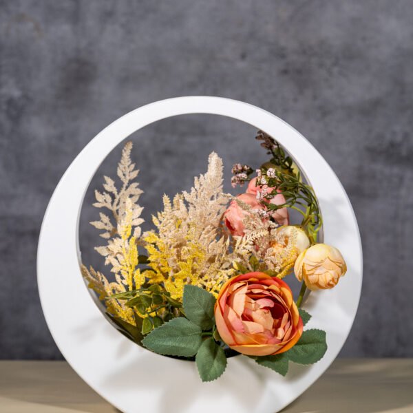 Artifical flowers and fooliage within a decorative,circular frame